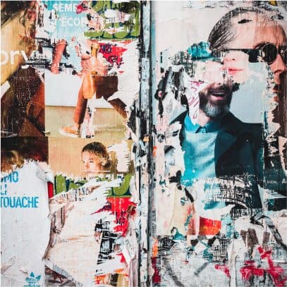 A wall of torn and layered fly posters with fragments of fashion photography still visible