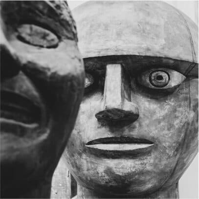Two carved wooden heads photographed in black and white