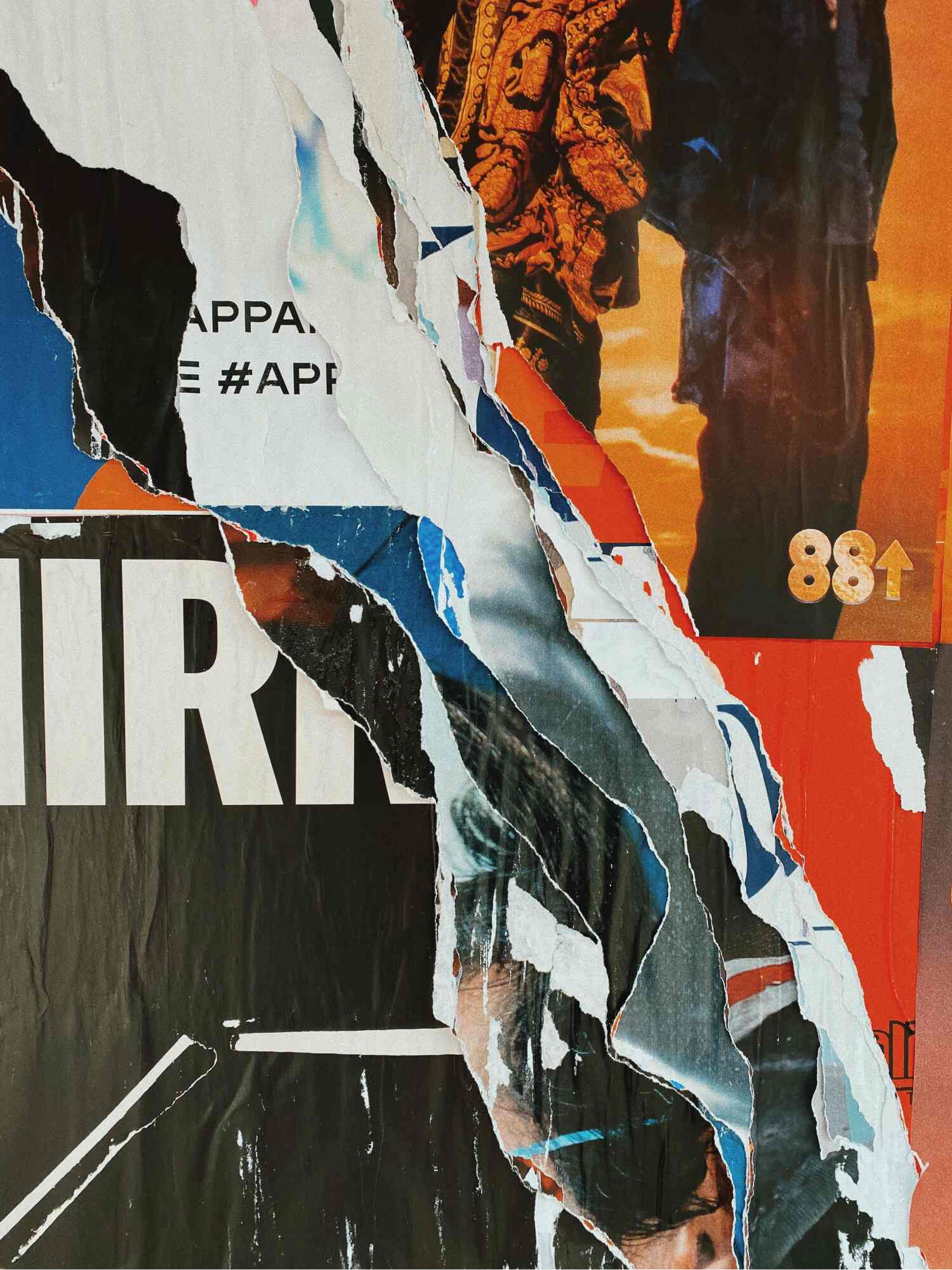 Layers of torn printed posters peeling away from a wall