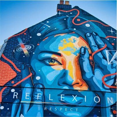 A blue and orange mural of a face with a hand raised beside it and the word REFLEXION painted beneath